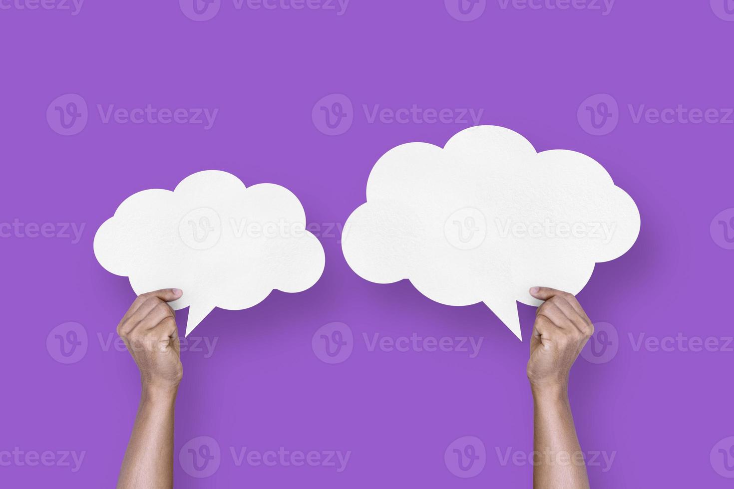 hand holding white paper cloud shape speech bubble balloon isolated on purple background communication bubbles photo
