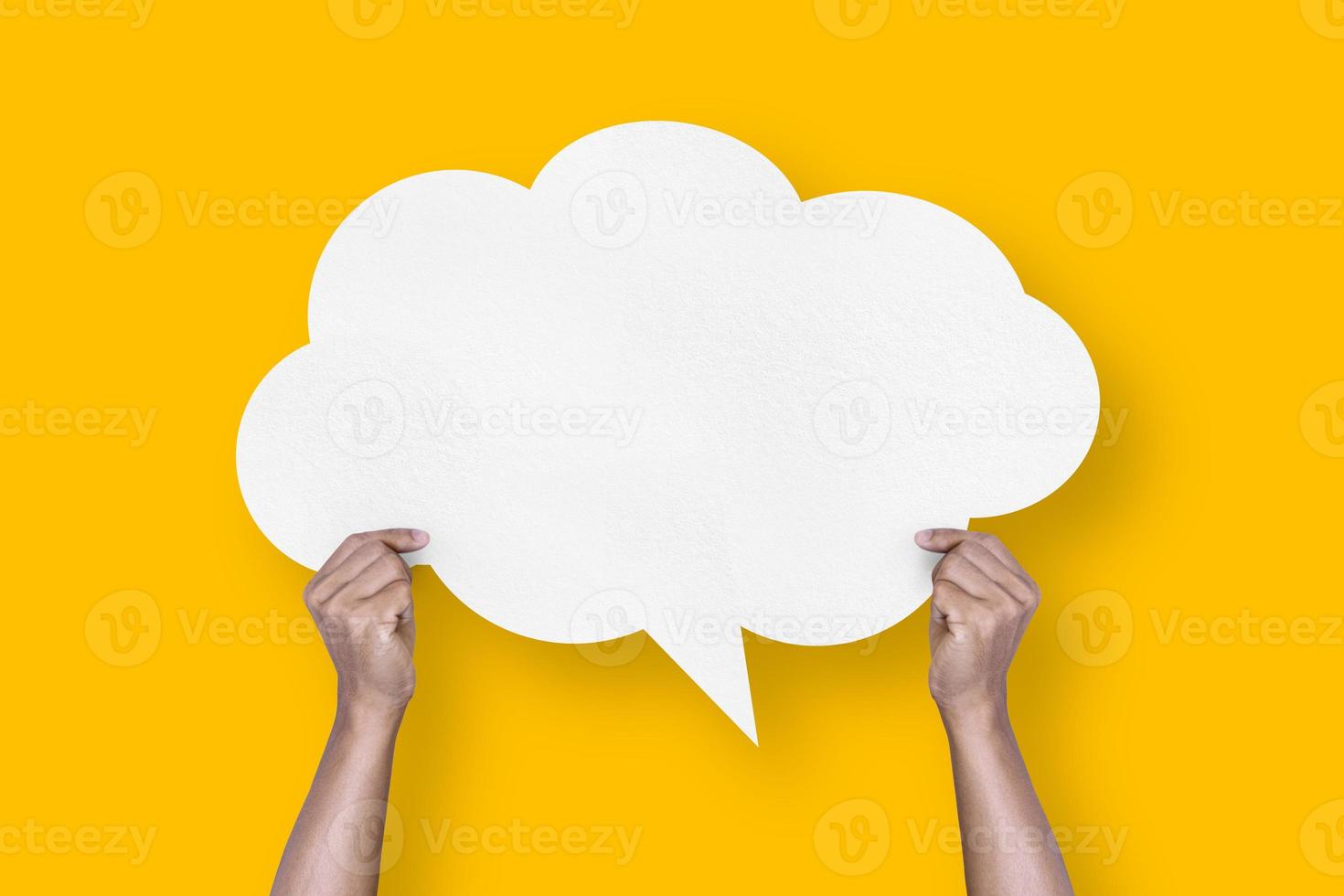 hand holding white paper cloud shape speech bubble balloon isolated on yellow background communication bubbles photo