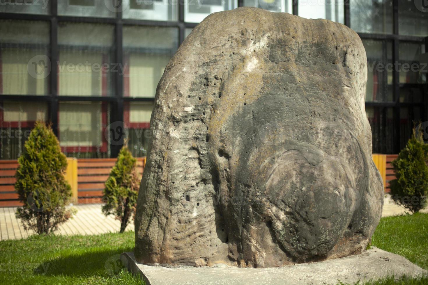 A large stone in the park. A block adorns the street. photo