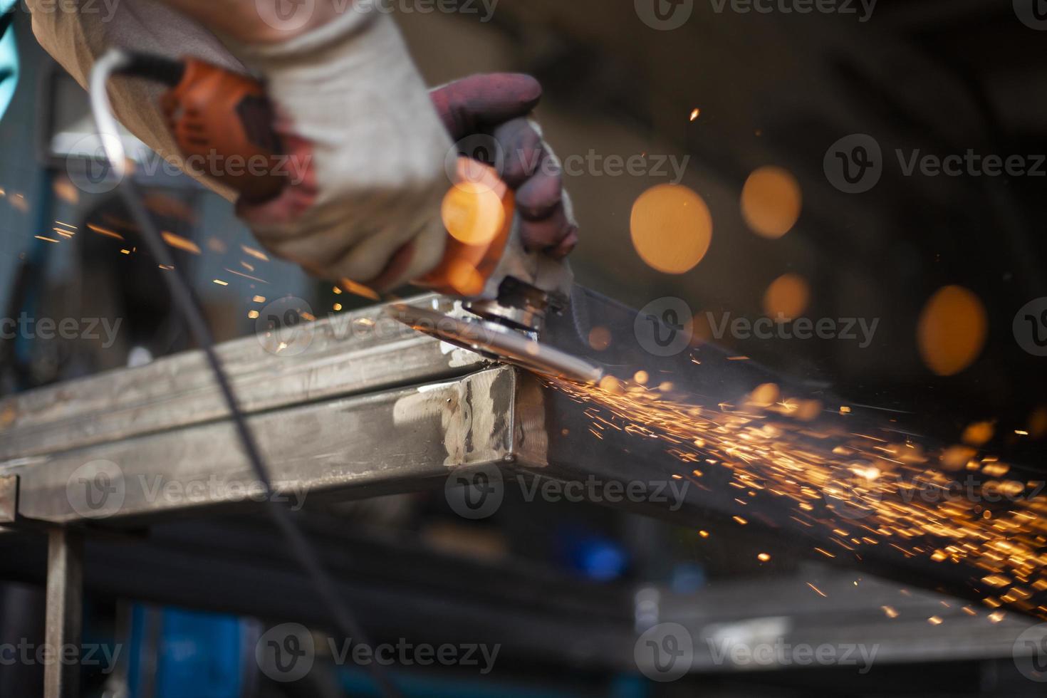 Work with a grinder for metal. Sparks from metal friction. A worker is grinding a part. Steel processing with an electric tool. photo