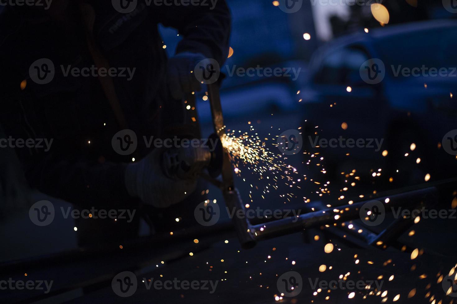 Sparks from grinding metal. Steel processing in workshop. Lights in dark. Production of parts. Cutting became grinder. photo