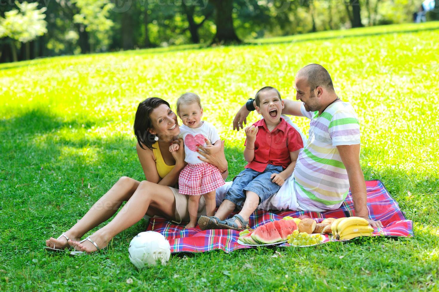 Feliz pareja joven con sus hijos divertirse en el parque foto