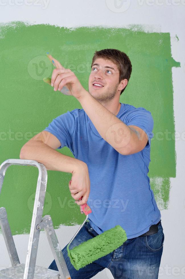 handsome young man paint white wall in color photo