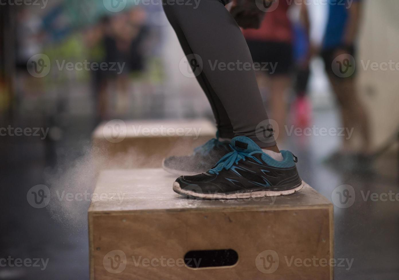 black woman is performing box jumps at gym photo