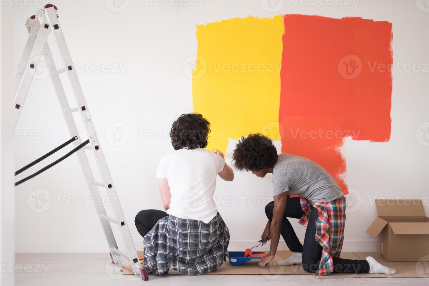 multiethnic couple painting interior wall photo