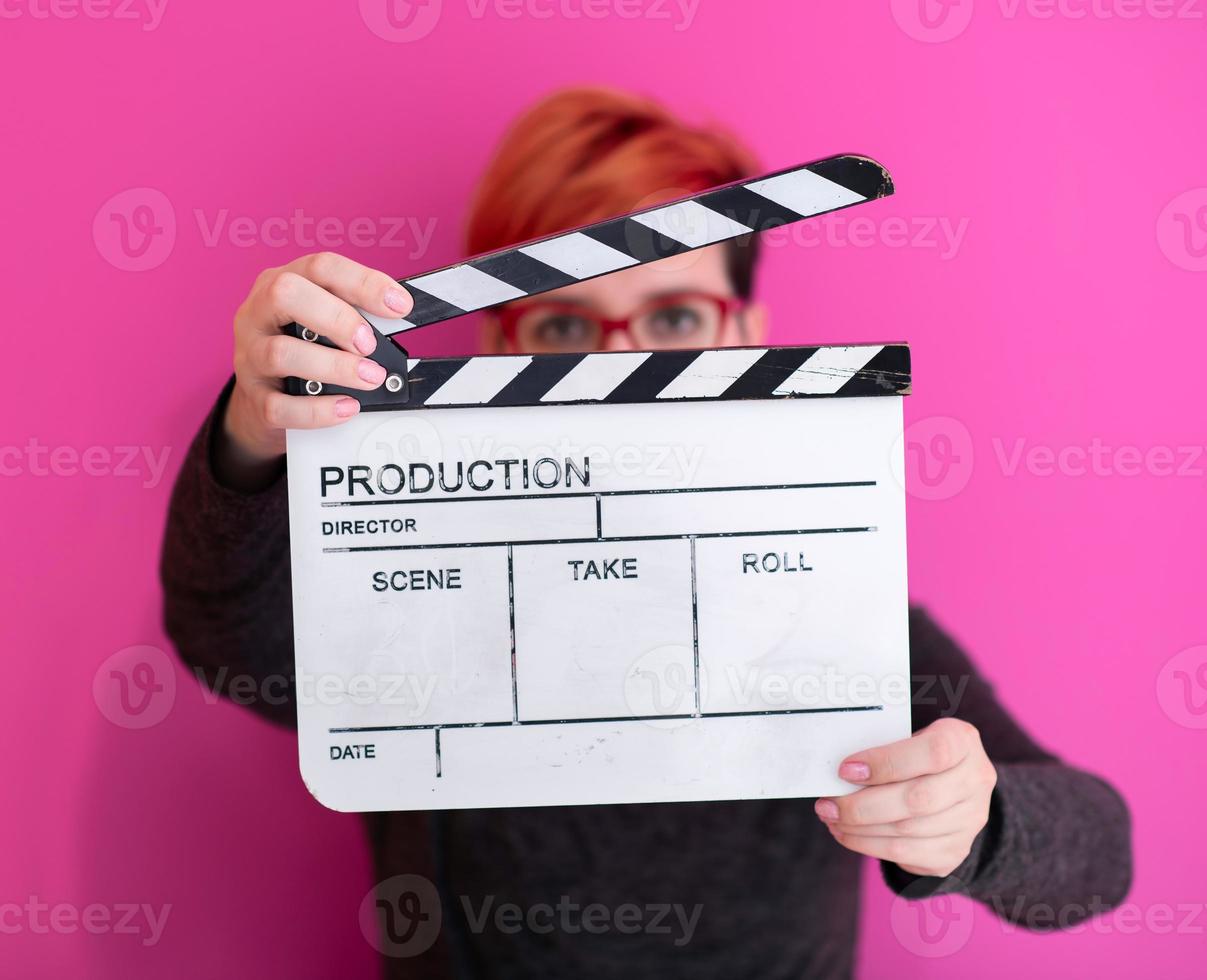 mujer pelirroja sosteniendo la chapaleta de la película sobre fondo rosa foto
