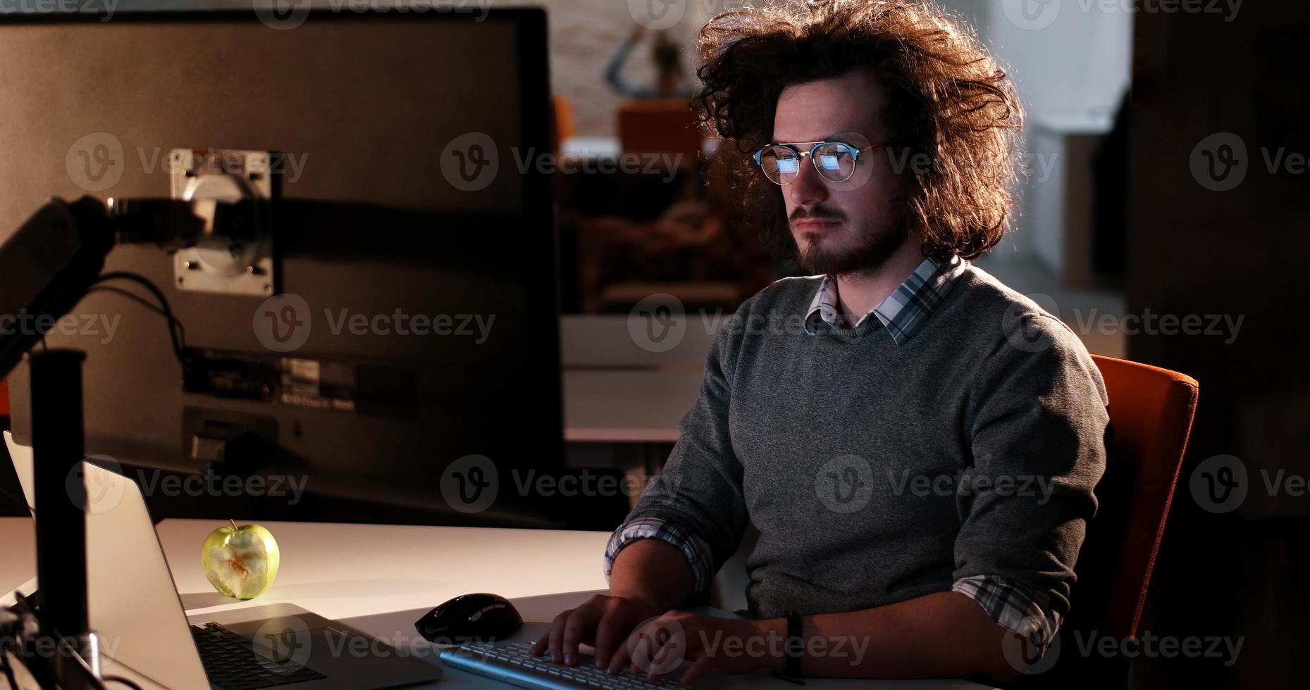 man working on computer in dark office photo