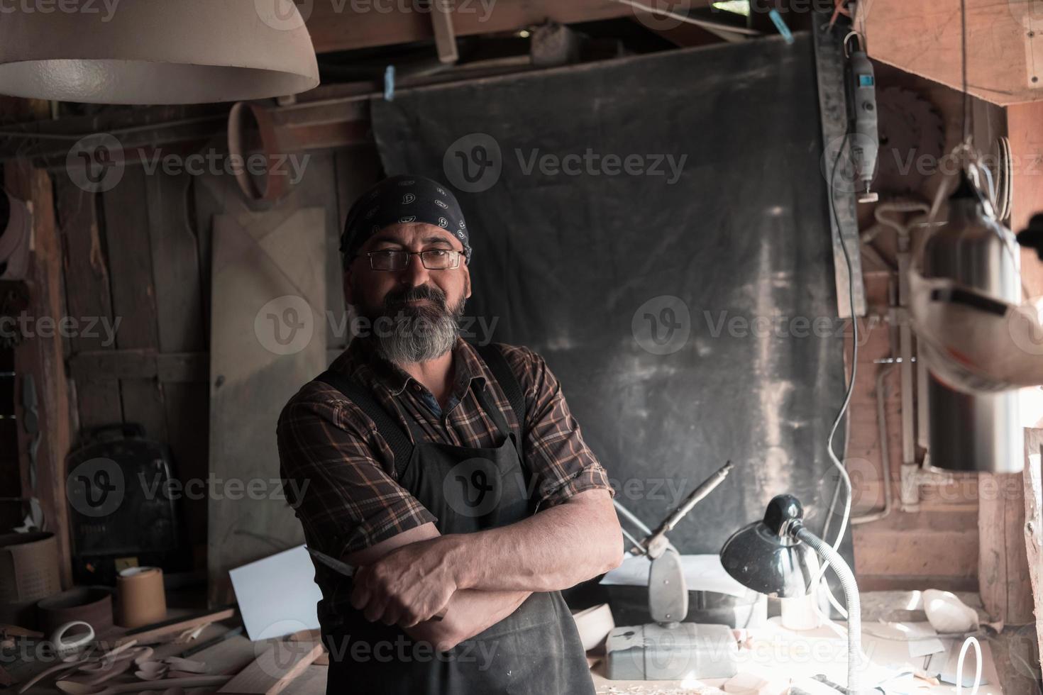 Spoon craft master in his workshop with handmade wooden products and tools photo