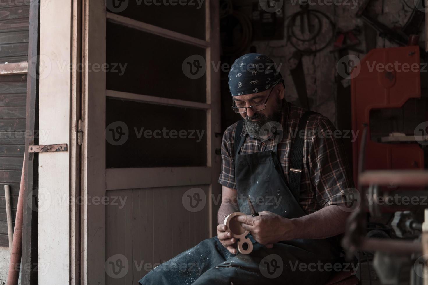 Spoon craft master in his workshop with handmade wooden products and tools working photo