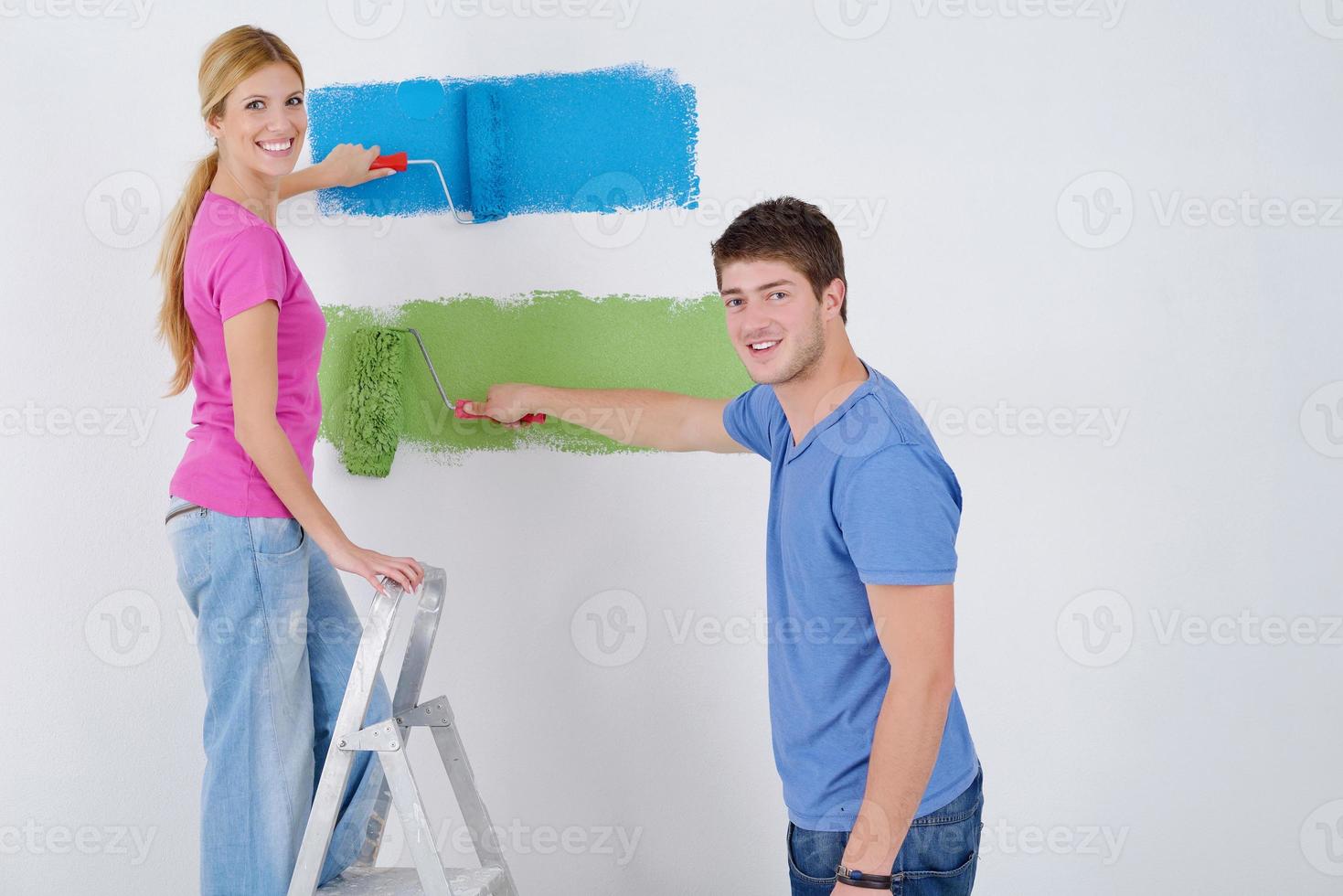 happy couple paint wall at new home photo