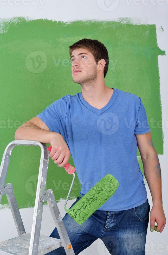 handsome young man paint white wall in color photo