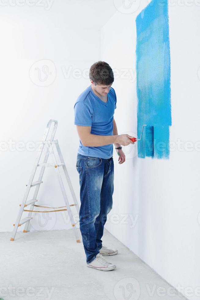 handsome young man paint white wall in color photo