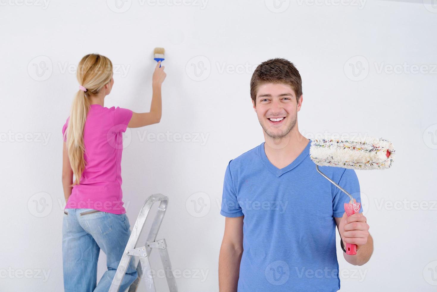 happy couple paint wall at new home photo