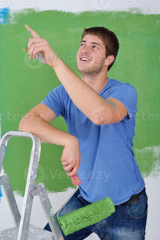 handsome young man paint white wall in color photo