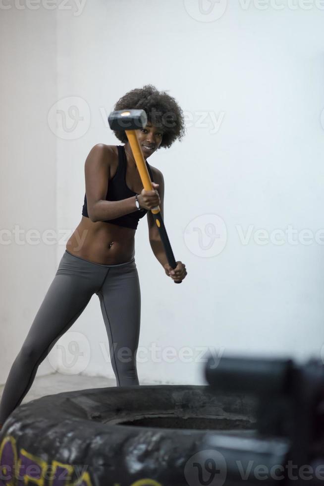 black woman workout with hammer and tractor tire photo