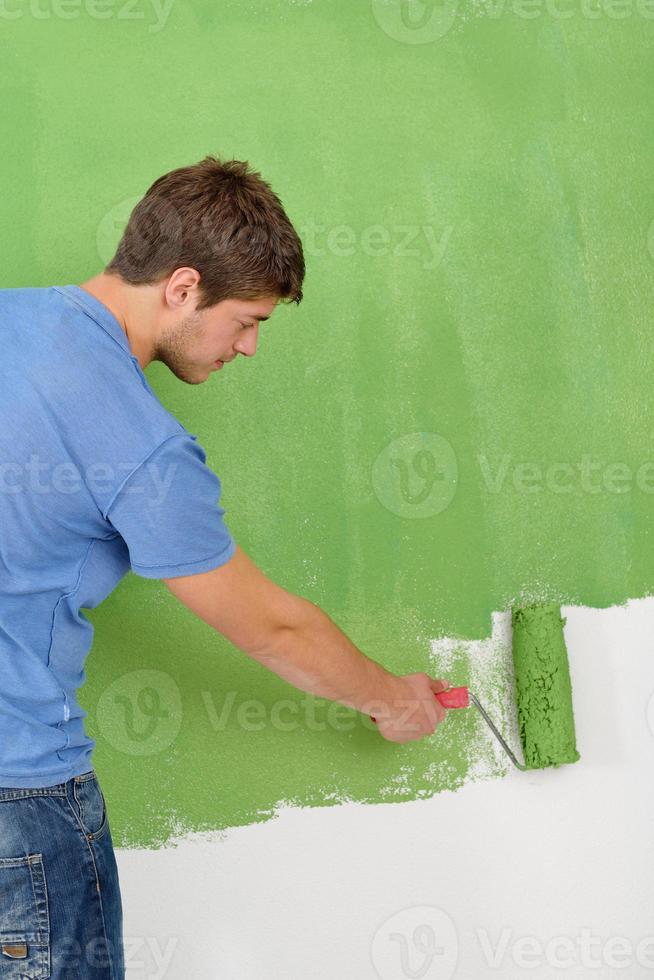 handsome young man paint white wall in color photo