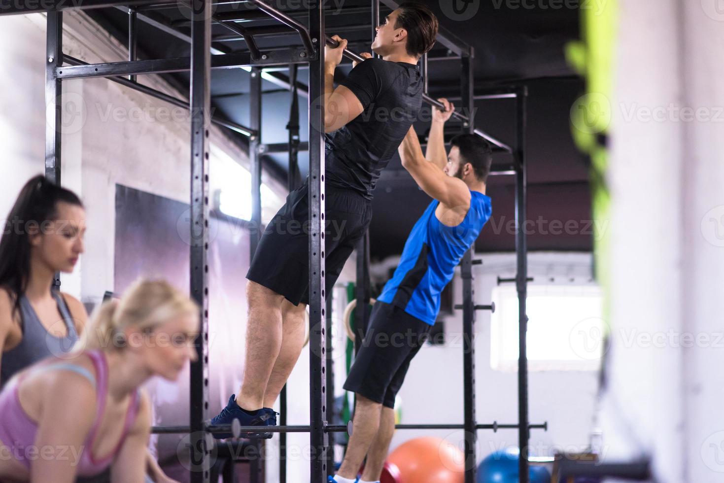 atletas jóvenes haciendo pull ups en la barra horizontal foto