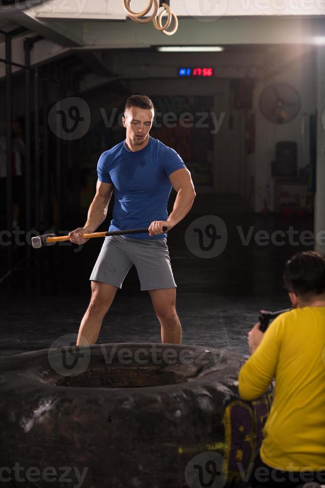 man workout with hammer and tractor tire photo