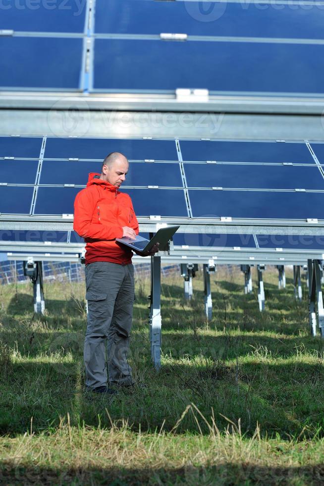 engineer using laptop at solar panels plant field photo