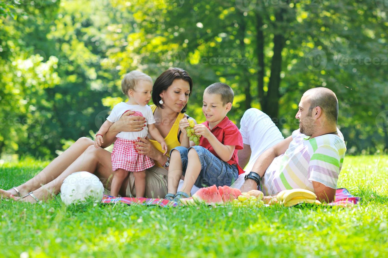 Feliz pareja joven con sus hijos divertirse en el parque foto