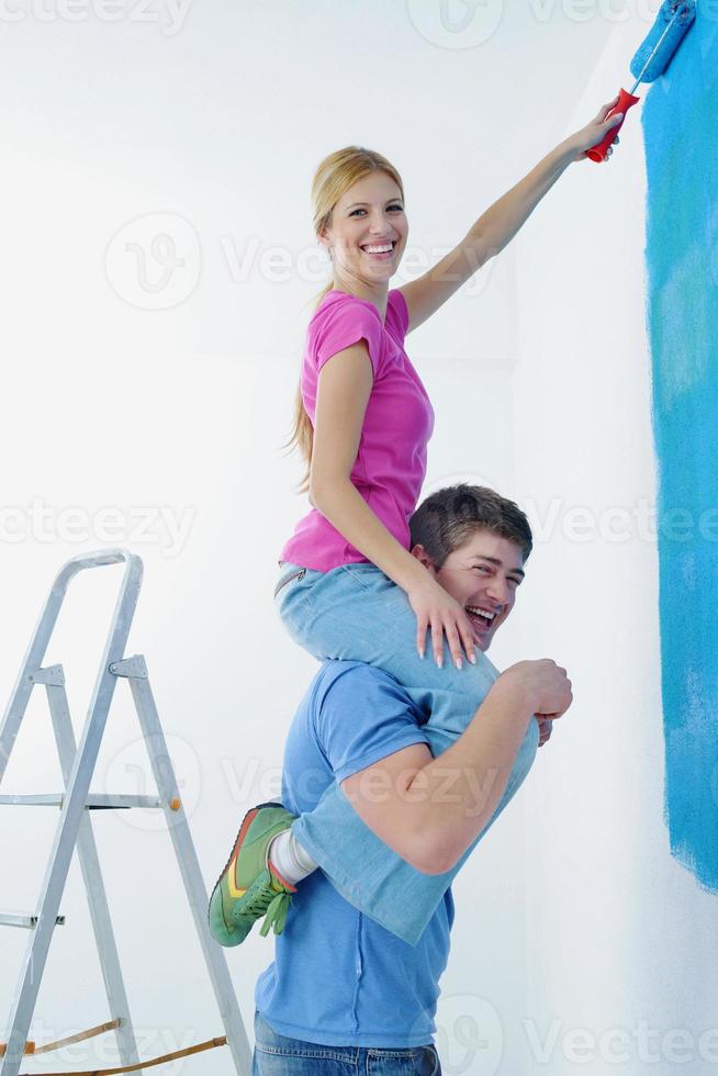 pareja feliz pintando una pared en su nuevo hogar foto