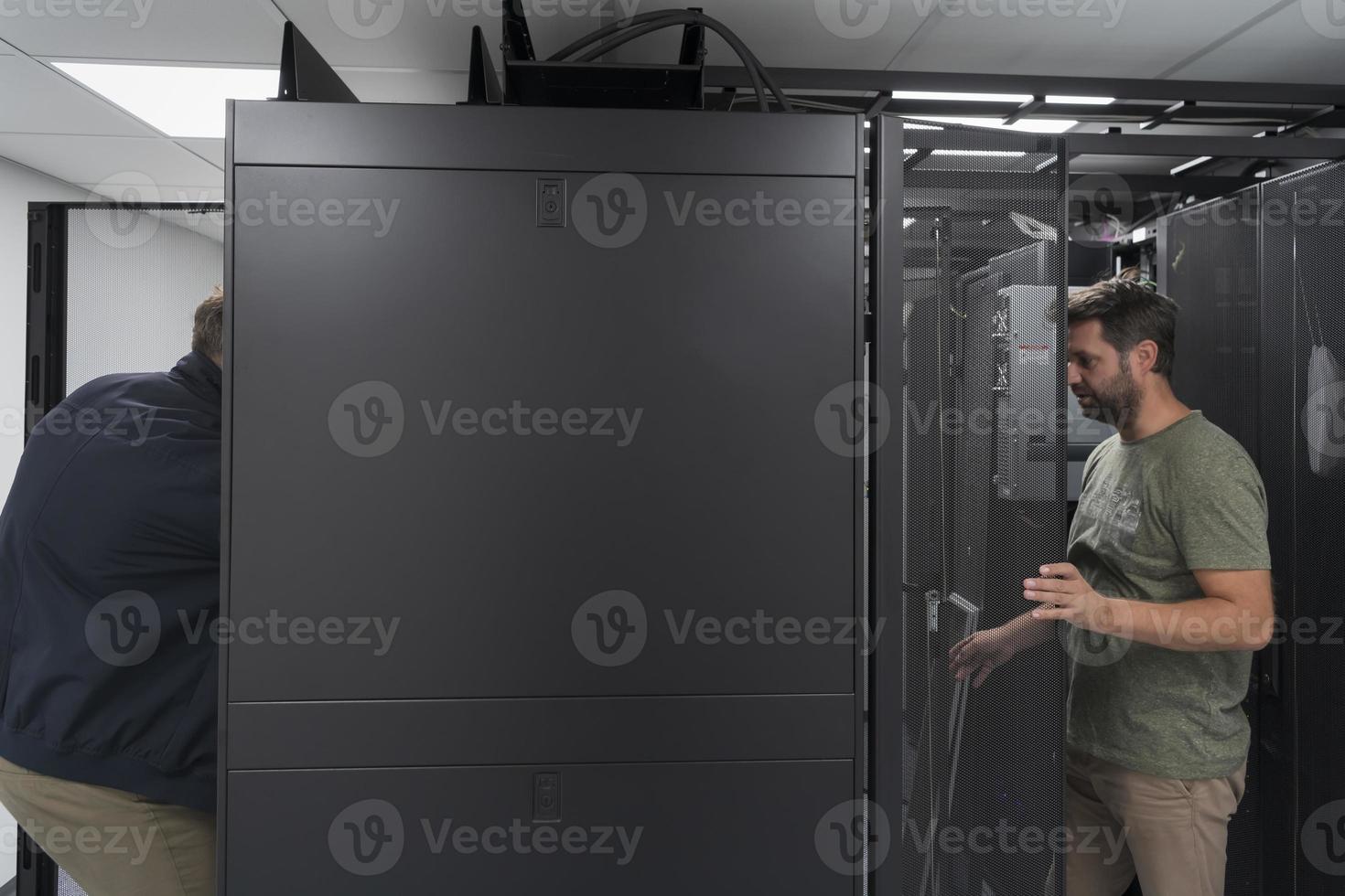 Technicians team updating hardware inspecting system performance in super computer server room or cryptocurrency mining farm. photo
