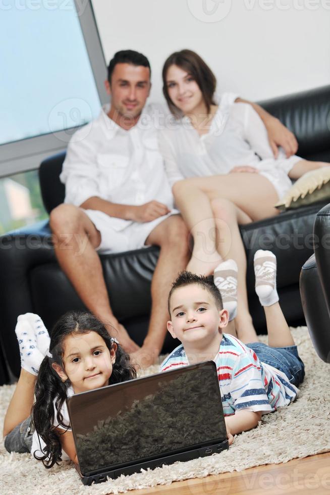 familia joven feliz divertirse y trabajar en la computadora portátil en casa foto