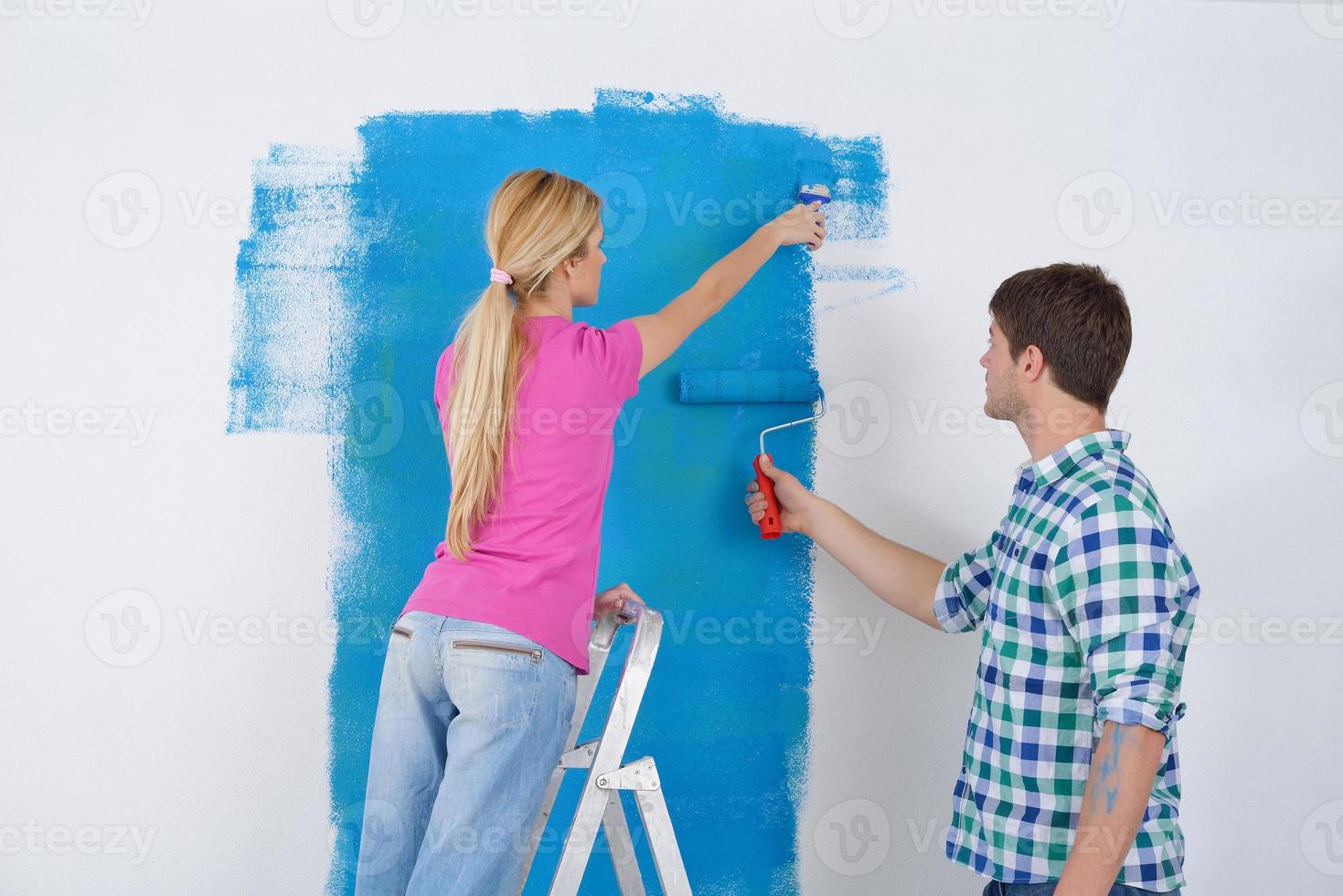 happy couple paint wall at new home photo