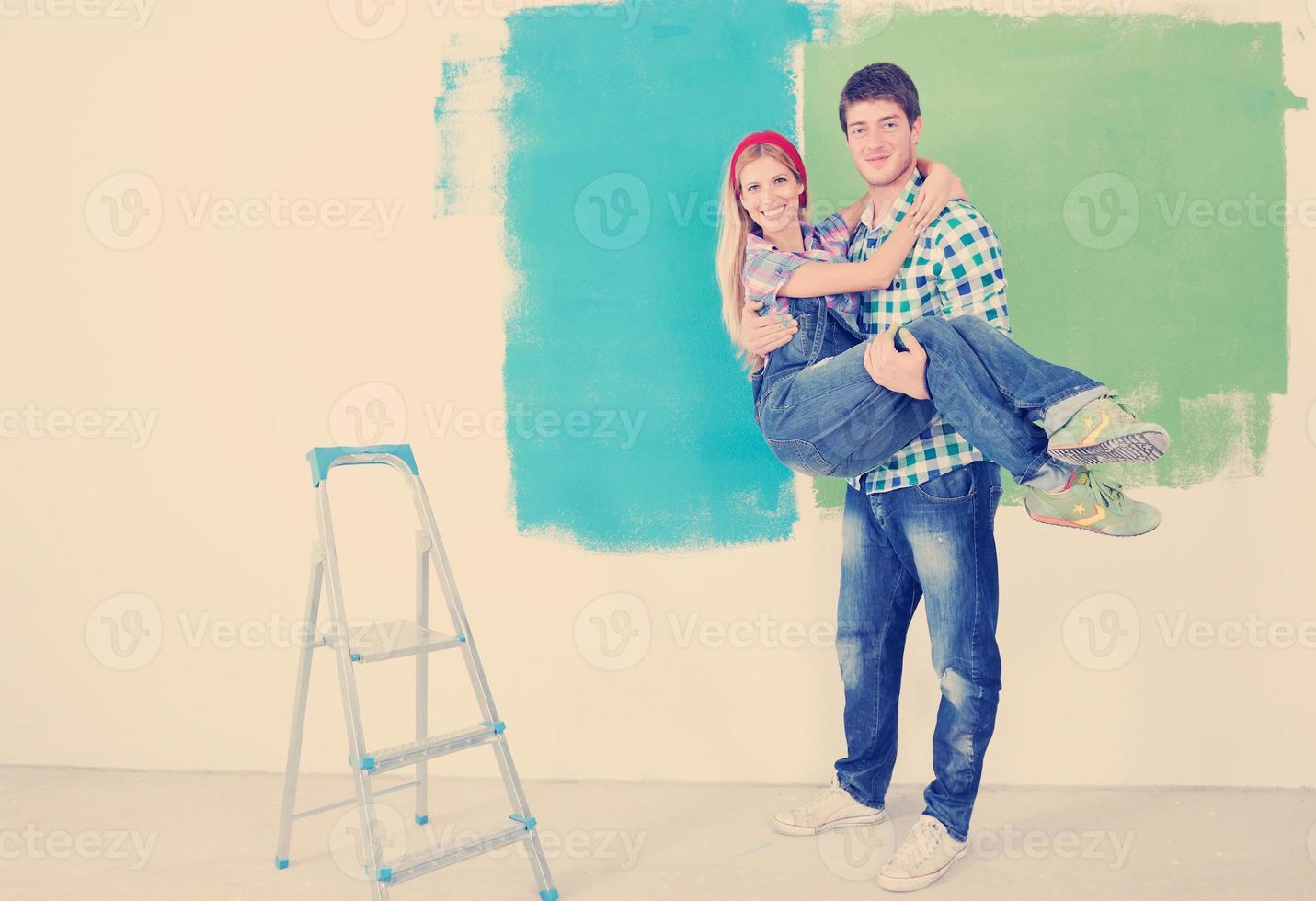 pareja feliz pintando una pared en su nuevo hogar foto