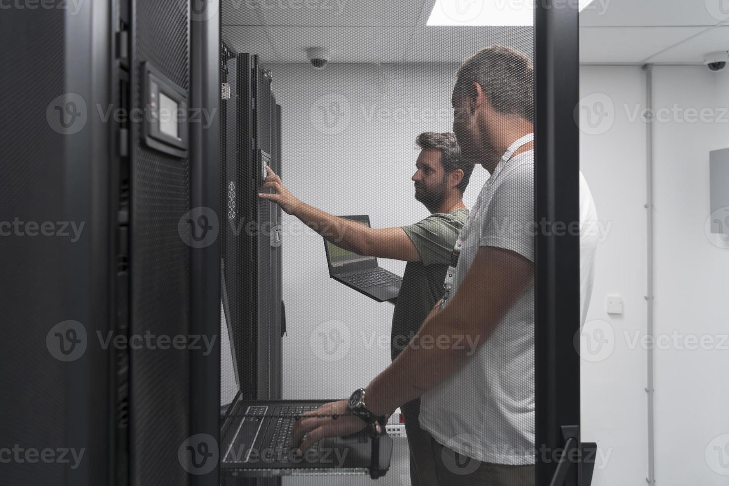 Technicians team updating hardware inspecting system performance in super computer server room or cryptocurrency mining farm. photo