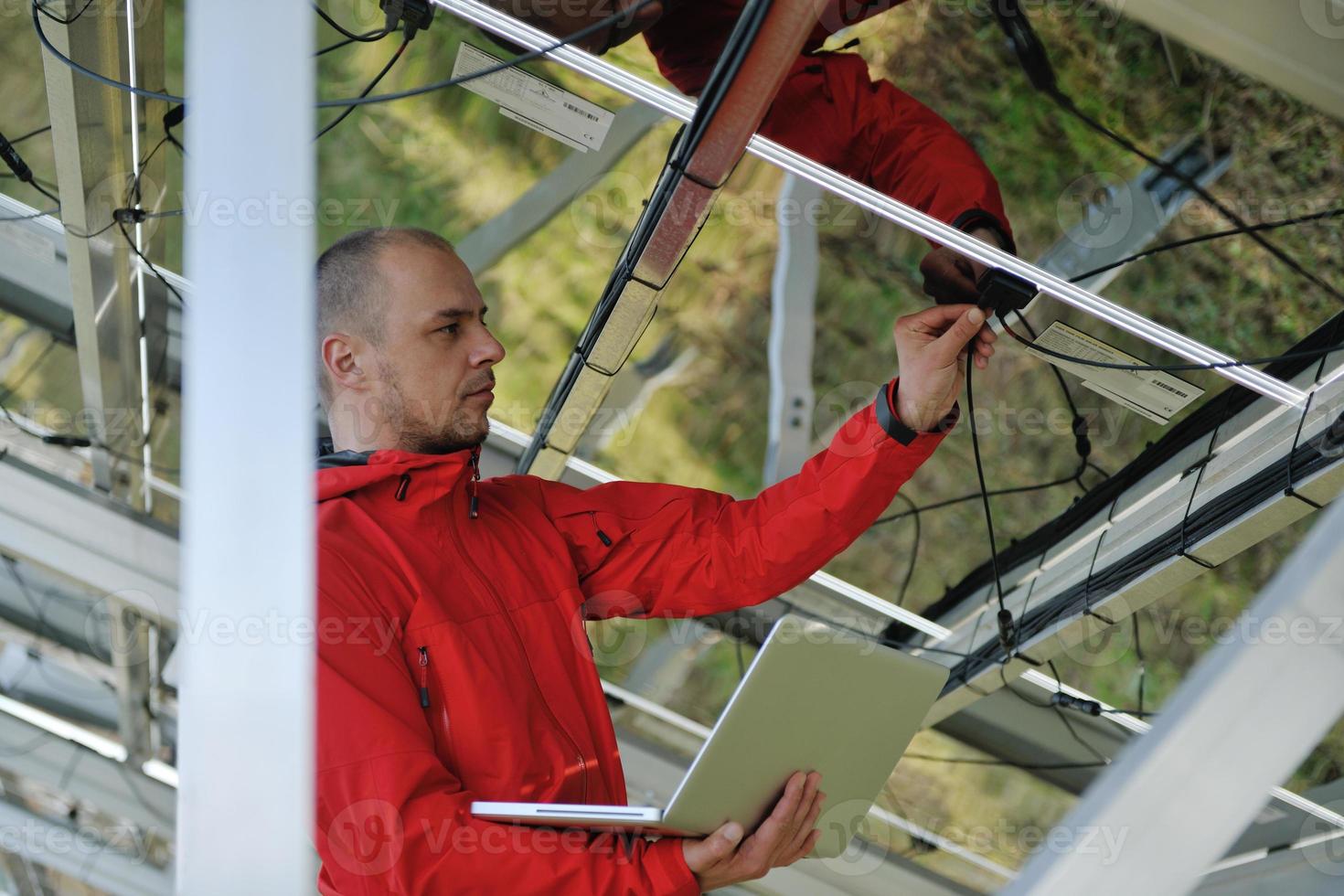 engineer using laptop at solar panels plant field photo