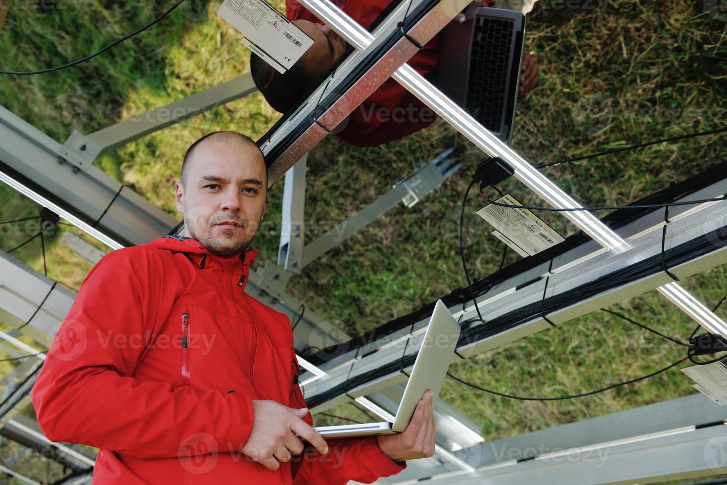 engineer using laptop at solar panels plant field photo