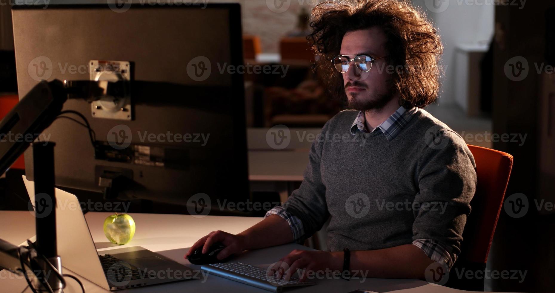 man working on computer in dark office photo
