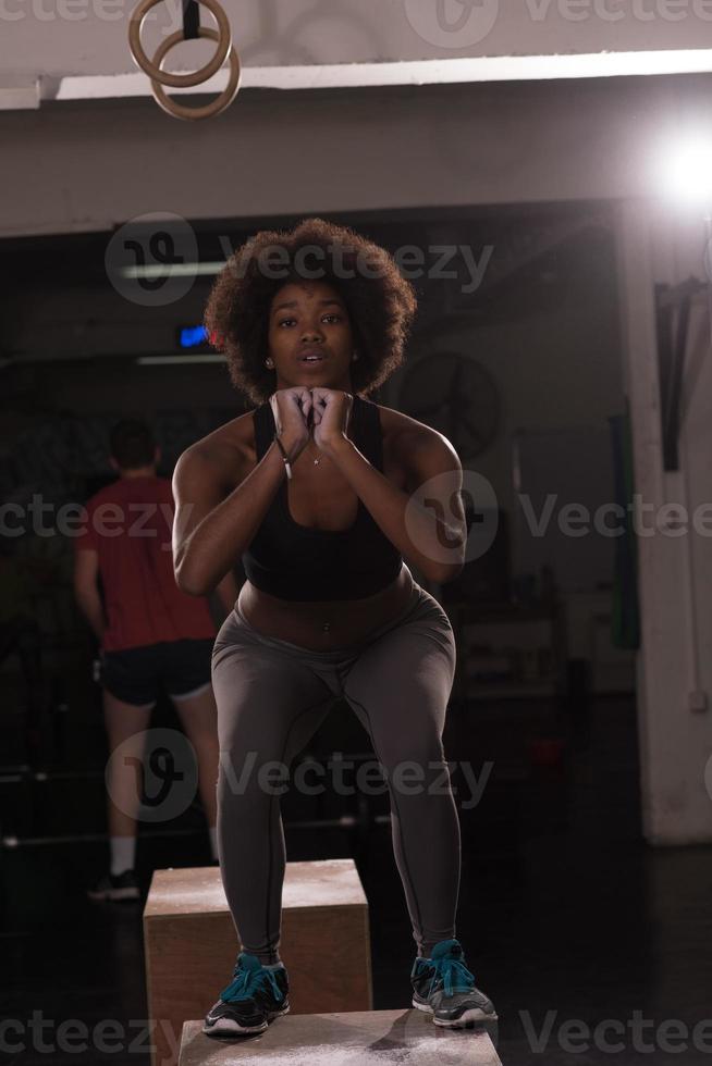 atleta femenina negra está realizando saltos de caja en el gimnasio foto