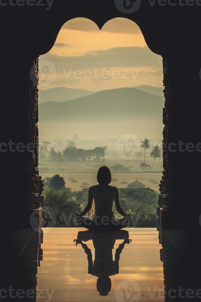 silueta joven practicando yoga en el templo al atardecer - efecto de color de estilo vintage foto