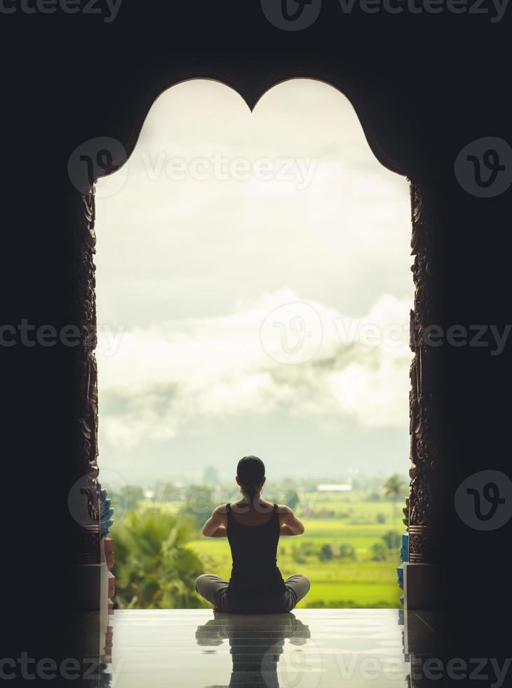 Silhouette young woman practicing yoga on the temple at sunset - vintage style color effect photo