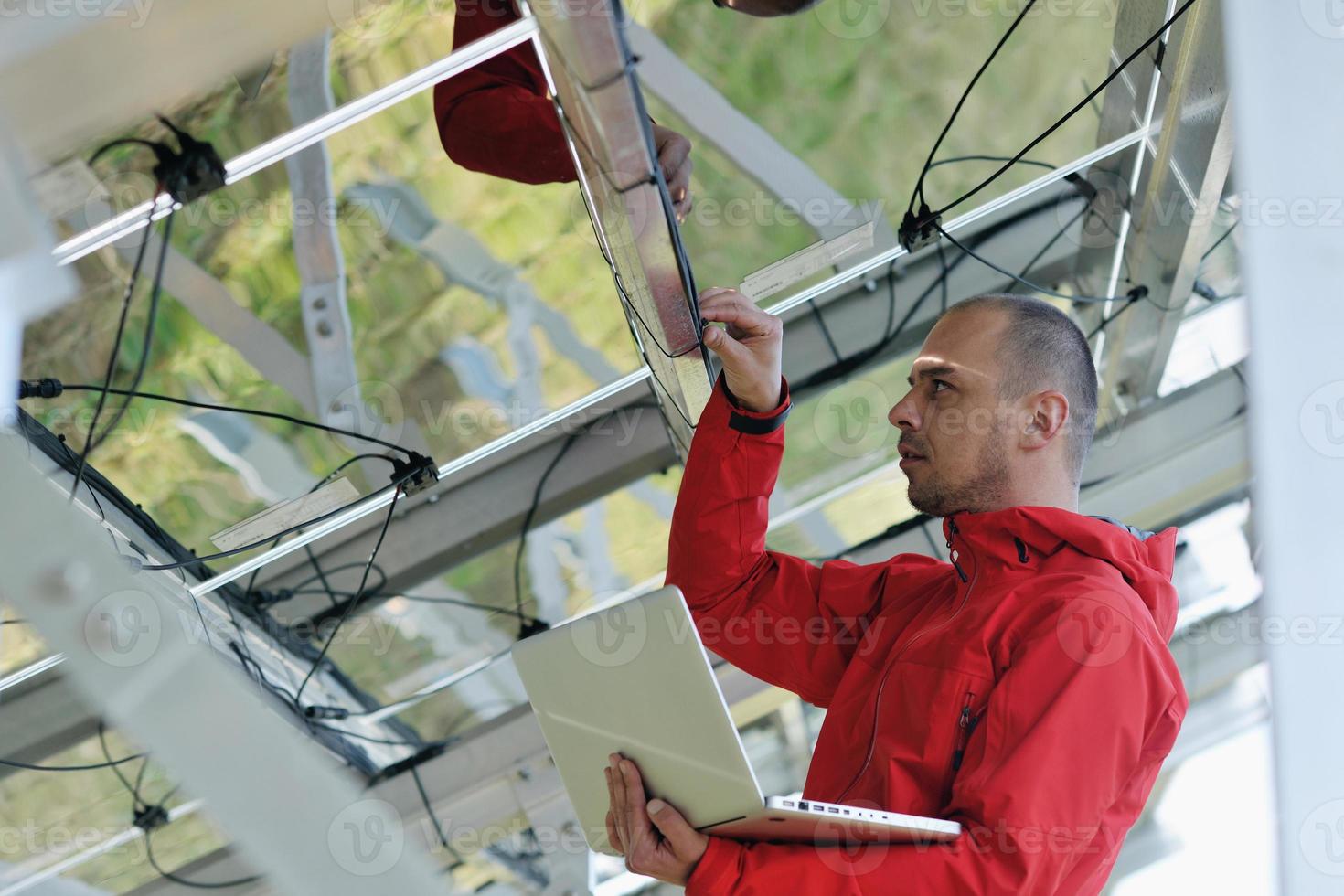 engineer using laptop at solar panels plant field photo