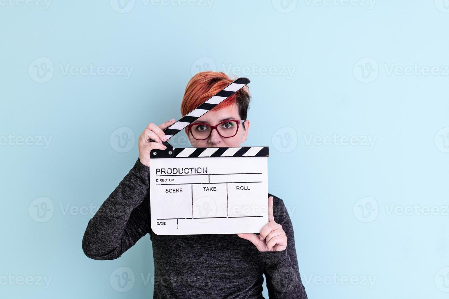 woman holding movie clapper against cyan background photo