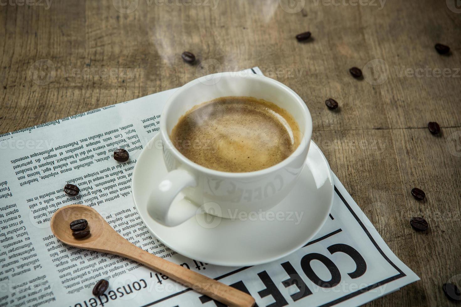 taza blanca de espresso con periódico en la mesa de madera por la mañana foto