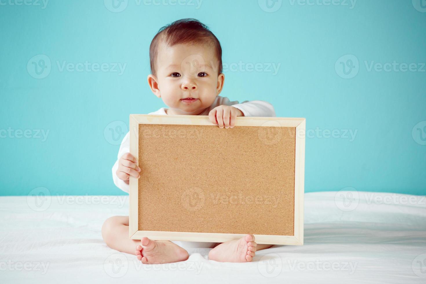 Infant child holding empty board, studio shot photo