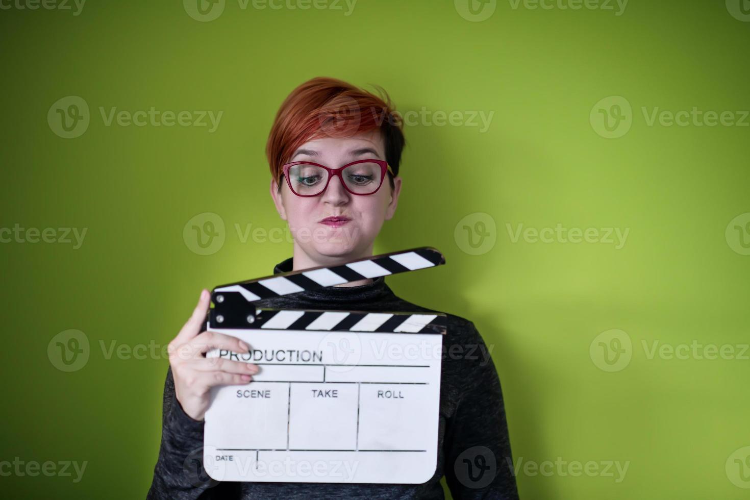 woman holding movie clapper against green background photo