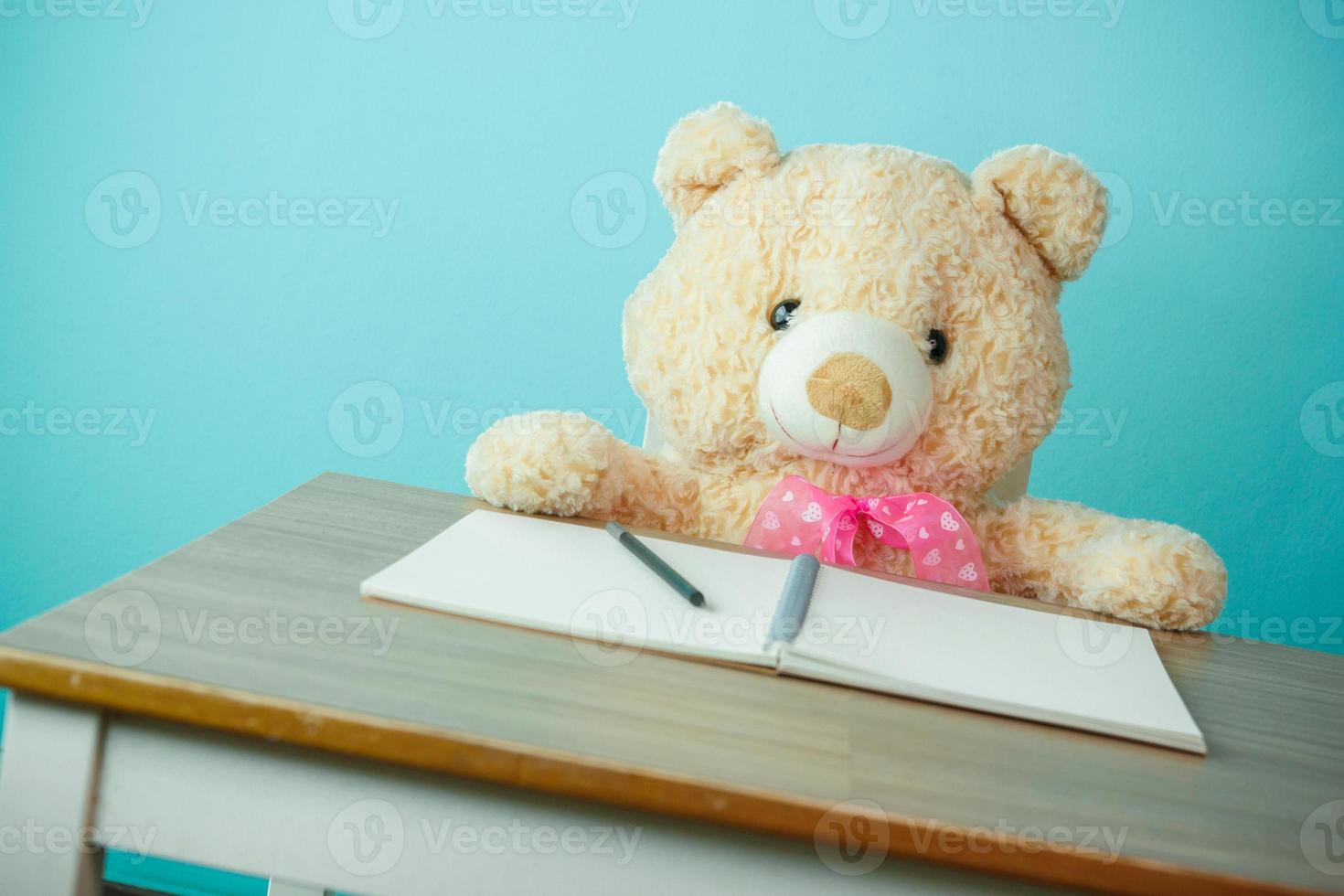 Conceptual shot of child education. Teddy bear writing on the table photo