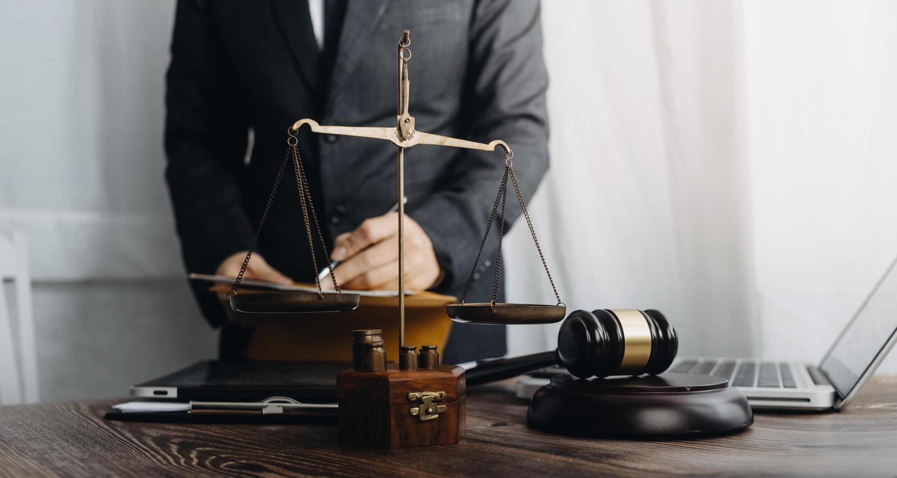 Justice and law concept.Male judge in a courtroom with the gavel, working with, computer and docking keyboard, eyeglasses, on table in morning light photo