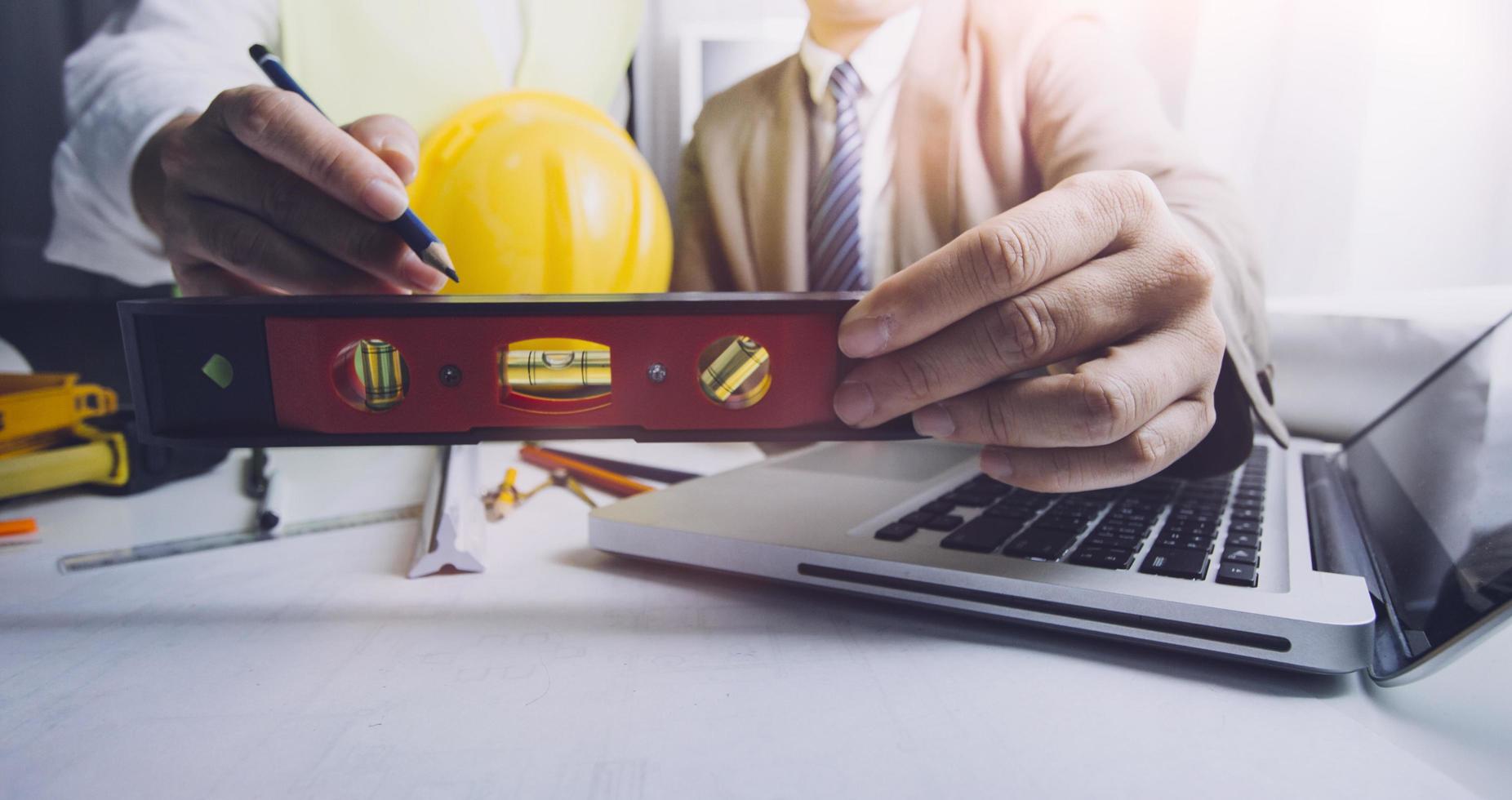 business hand working and laptop with on on architectural project at construction site at office desk in office photo
