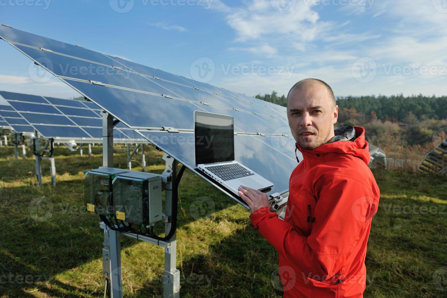 engineer using laptop at solar panels plant field photo