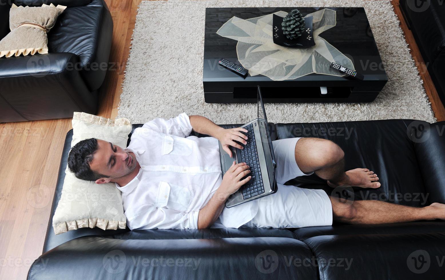 Portrait of a relaxed young guy using laptop at home photo