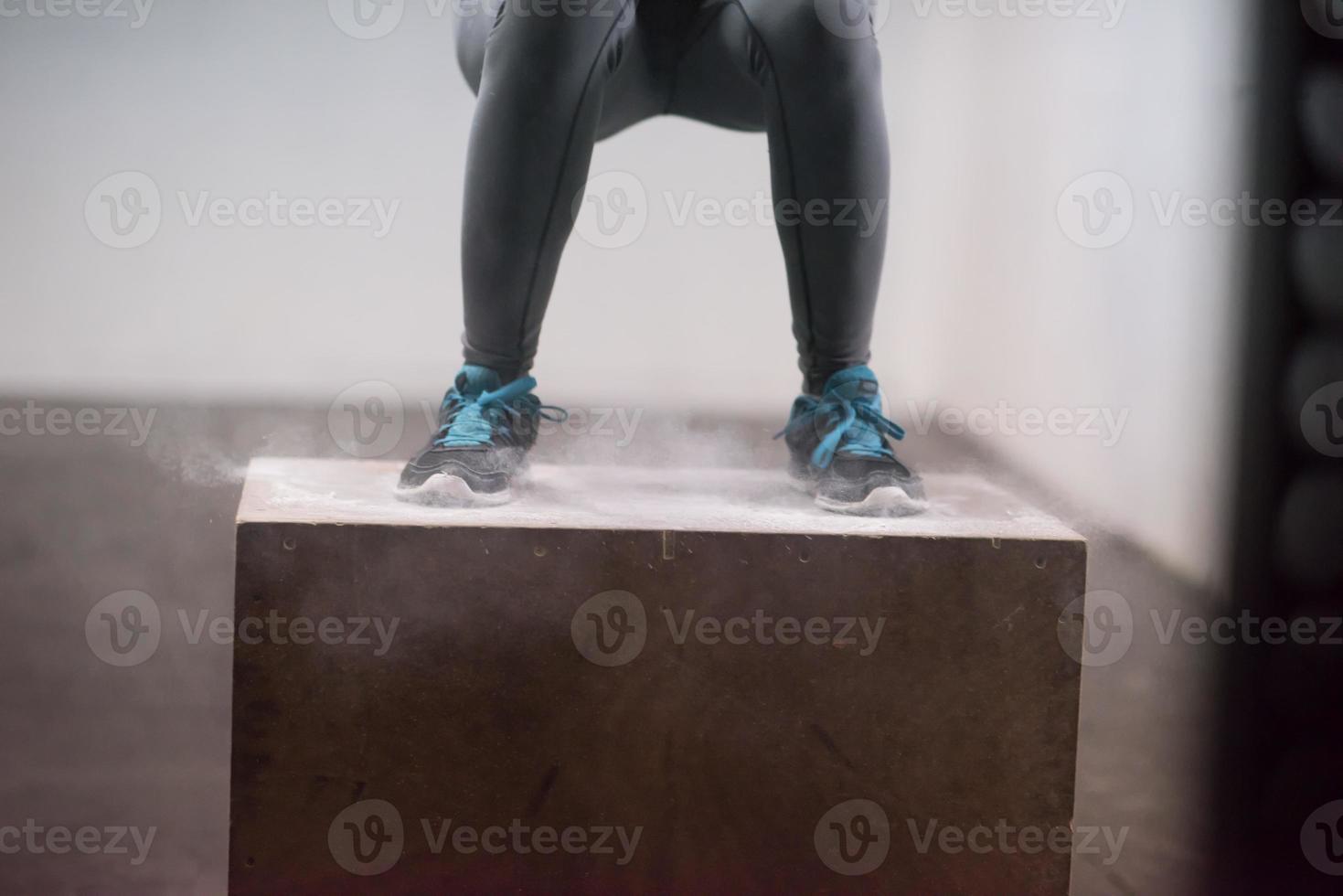 black woman is performing box jumps at gym photo