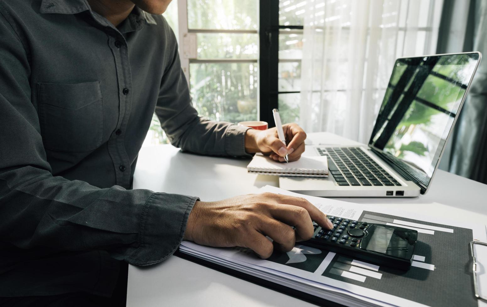 Business accounting concept, Business man using calculator with computer laptop, budget and loan paper in office. photo
