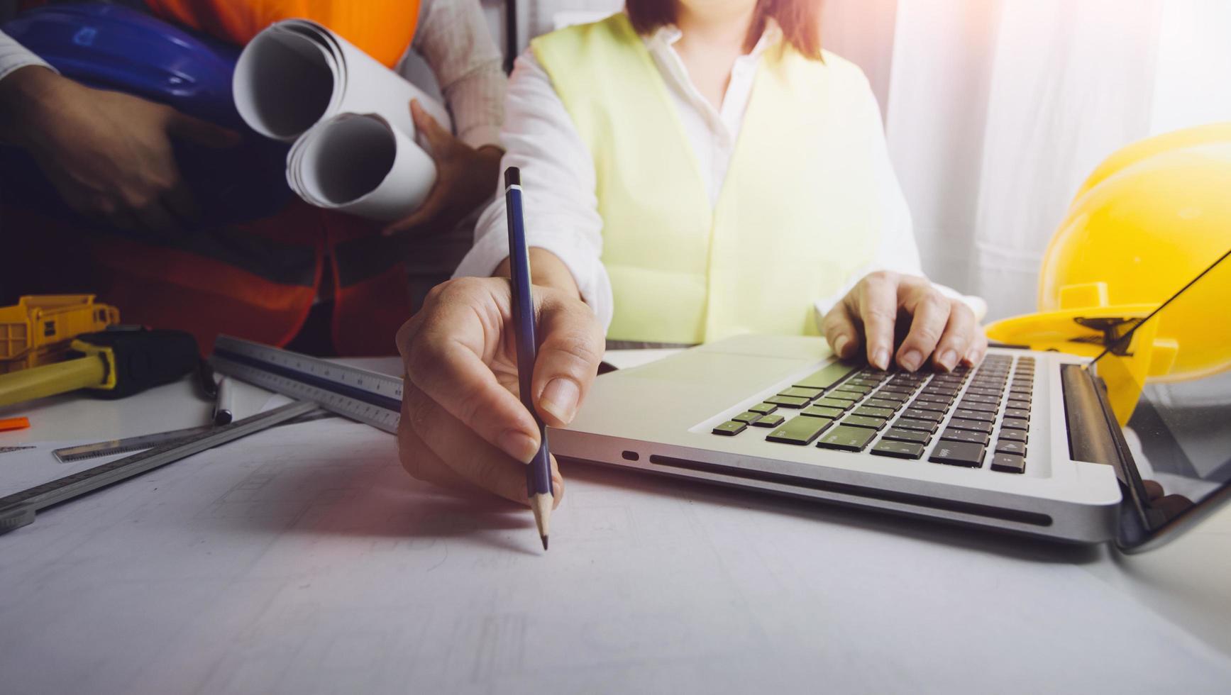 business hand working and laptop with on on architectural project at construction site at office desk in office photo