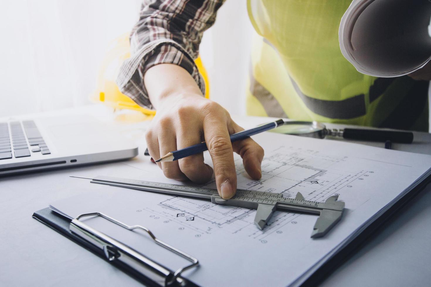 Two colleagues discussing data working and tablet, laptop with on on architectural project at construction site at desk in office photo